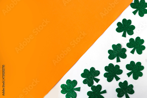 Happy St. Patricks Day. Shamrocks pattern on white and orange background. Patrick Day symbols on Ireland flag background. Copy space for the text