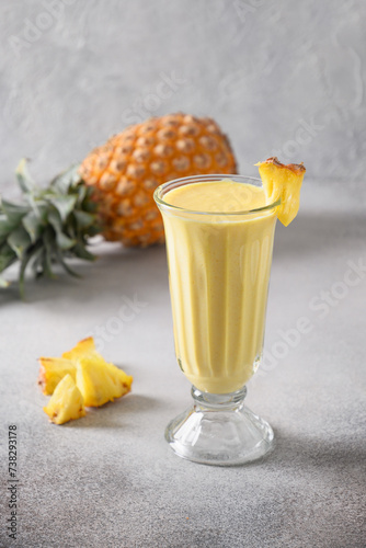 Asian traditional Pineapple lassi on gray background. Freshness cold beverage made of yogurt, water, spices, fruits and ice. Popular beverage in India and Sri lanka. Vertical format.