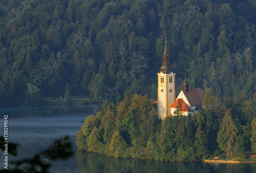 close up view of tiny island with church tower and nature in the middle of gorgeous clear water blue lake photo