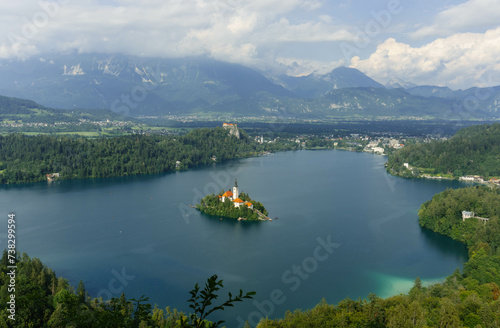 tiny island with church tower and nature in the middle of gorgeous clear water blue lake photo