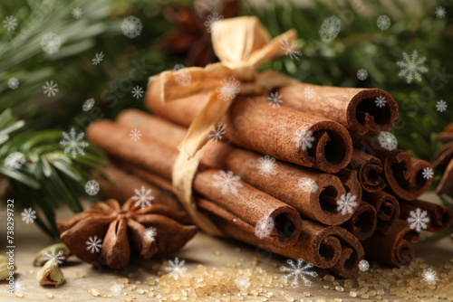 Different spices and fir tree branches on wooden table, closeup. Cinnamon, anise, cardamom