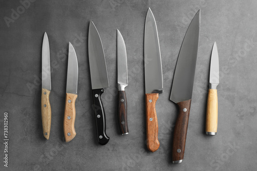Many different knives on grey textured table, flat lay