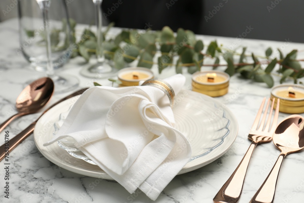 Beautiful place setting with candles and eucalyptus on white marble table
