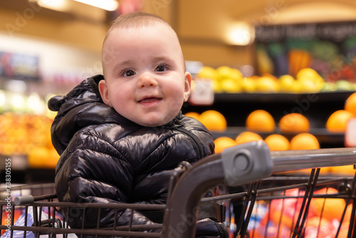 Adorable baby boy in a shopping cart at a grocery store