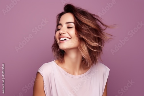 Portrait of beautiful young woman with flying hair over purple background.