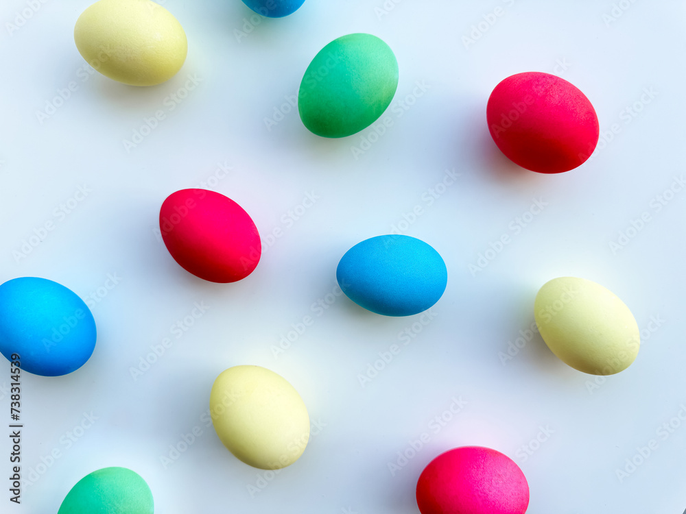 Colorful Easter eggs scattered on white background, flat lay composition for spring holiday celebration and decoration ideas. For Easter holiday promotions, themed party invitations, seasonal blog