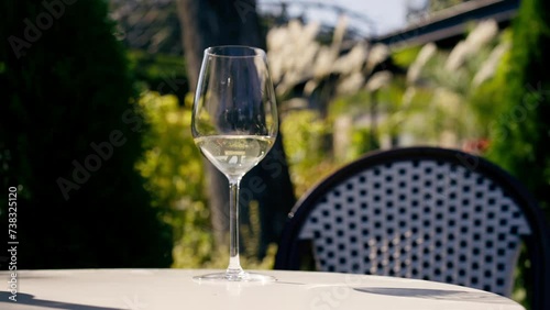 Close-up of a glass wineglass with white wine for tasting standing on a table in a sunny garden