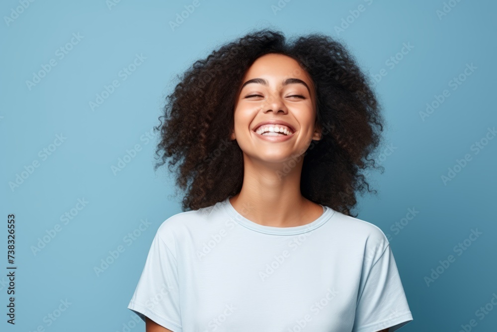 Portrait of a happy young african american woman laughing against blue background Portrait of a happy young african american woman laughing against blue background