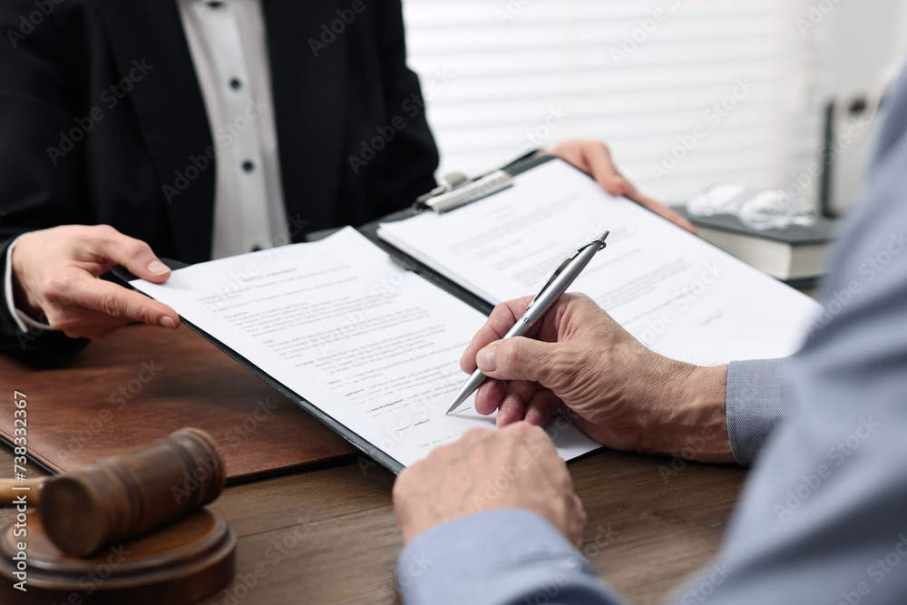 Senior man signing document in lawyer's office, closeup Senior man signing document in lawyer's office, closeup