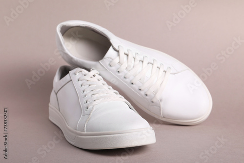 Pair of stylish white sneakers on grey background