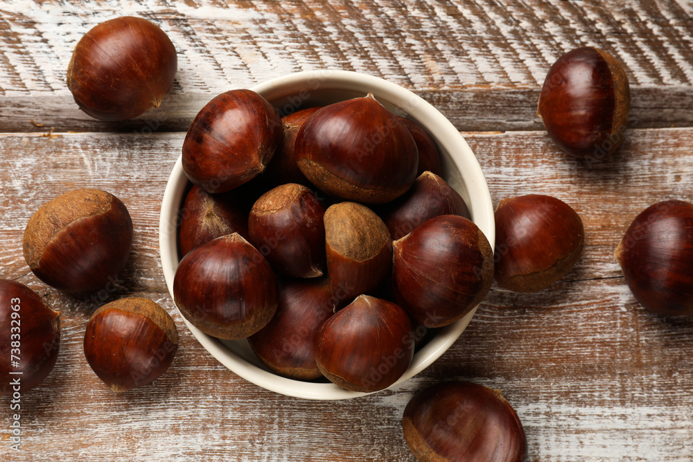 Sweet fresh edible chestnuts in bowl on wooden table, top view Sweet fresh edible chestnuts in bowl on wooden table, top view