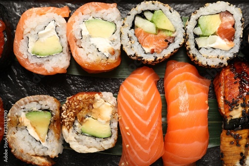 Set of delicious sushi rolls on board, top view