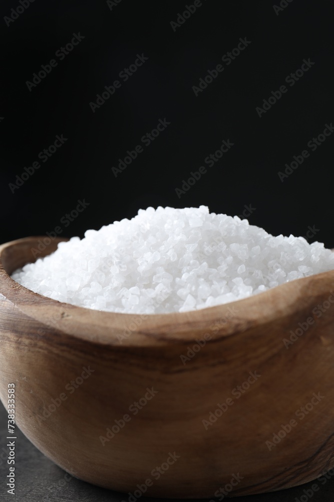 Natural salt in wooden bowl on table, closeup