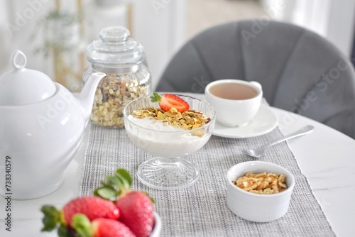 Muesli with yogurt and strawberries, tea.  Healthy breakfast.