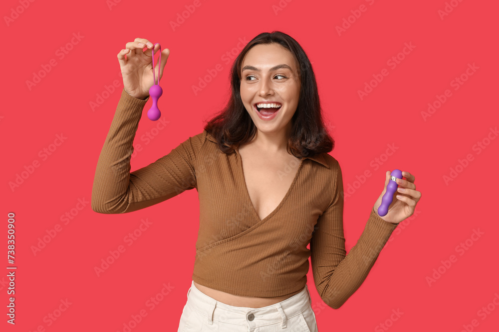 Happy young woman with different sex toys on red background Happy young woman with different sex toys on red background