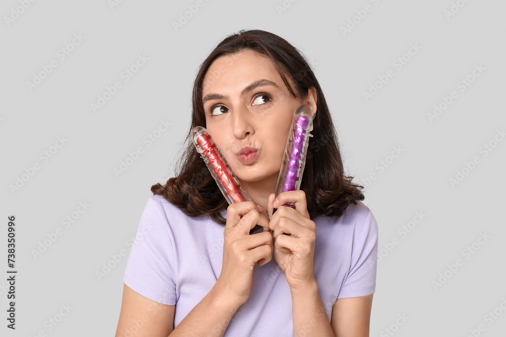 Thoughtful young woman with vibrators on grey background Thoughtful young woman with vibrators on grey background
