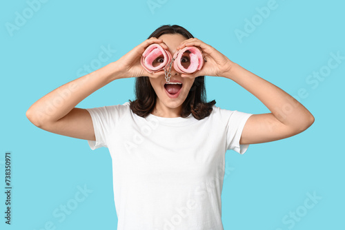 Funny young woman with handcuffs on blue background