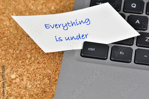 Everything is under control concept. Laptop keyboard with everything is under words on a white paper under the control key. photo