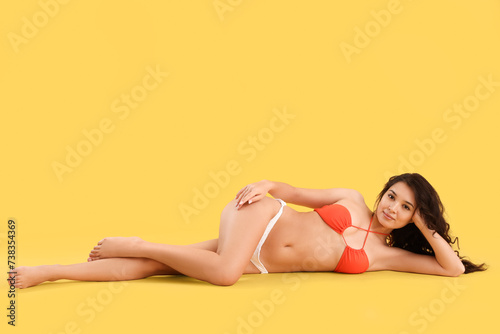 Sexy young woman in swimsuit on yellow background