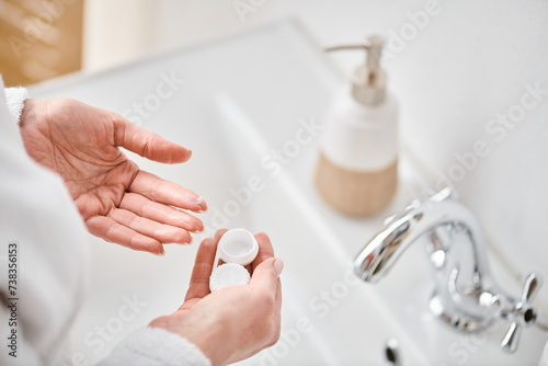 cropped view of adult woman in bathrobe holding her contact lenses before wearing them in bathroom photo