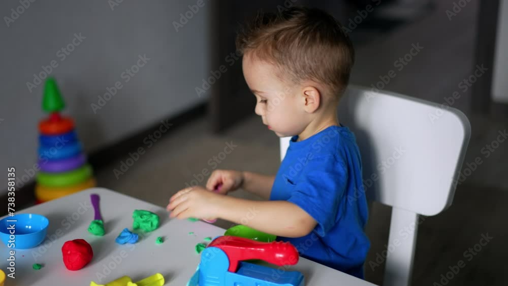 Little toddler is totally absorbed by his game. Useful hobby of sculpturing with plasticine.
