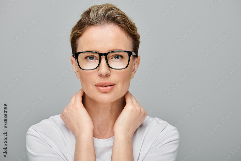 appealing blonde female model with blonde hair and glasses looking at camera on gray backdrop appealing blonde female model with blonde hair and glasses looking at camera on gray backdrop