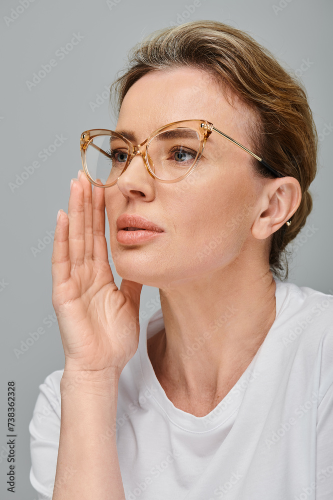 good looking blonde female model with glasses and collected hair in posing on gray background good looking blonde female model with glasses and collected hair in posing on gray background