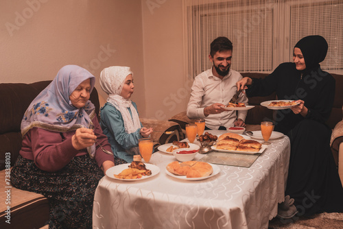 Happy Muslim family having iftar dinner during Ramadan dining table at home.