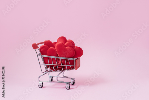 Shopping cart loaded with red decorative hearts. Valentine's day sale concept. Selective focus, copy space