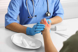 Doctor examining patient's burned hand at table, closeup