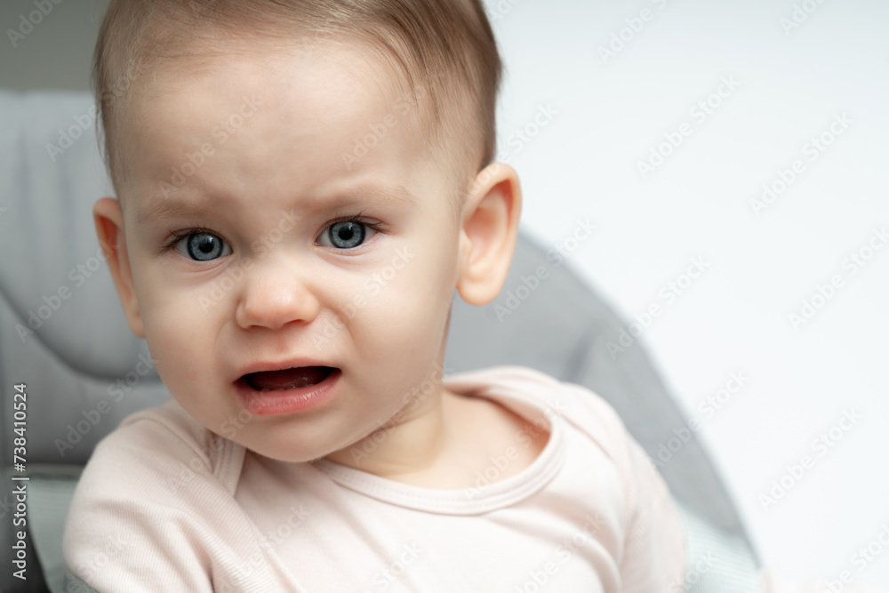 Portrait of crying 1-year old baby upset of being hungry and tired