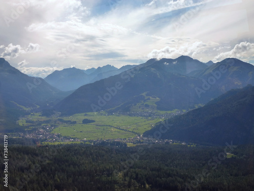 A village near a large forest is located in a picturesque valley between mountains. View from a distance