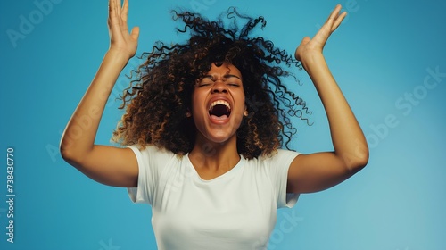 Curly optimistic woman raises palms from joy happy to receive awesome present from someone shouts loudly dressed in casual white t shirt isolated on blue background Excited Afro female : Generative AI