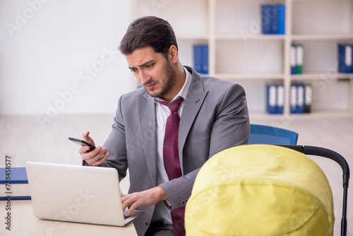 Young male employee looking after newborn at workplace