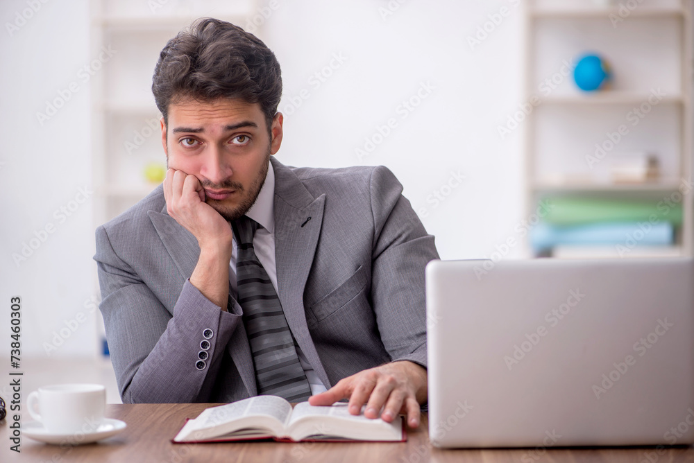 Young male employee reading book in the office Young male employee reading book in the office