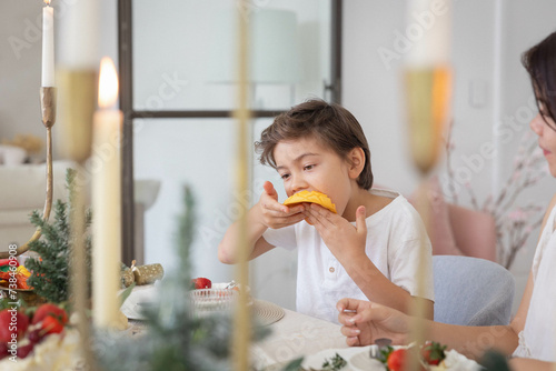 Boy eating slice of mango at christmas table photo