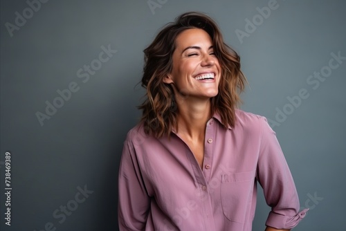Portrait of a beautiful young woman laughing against grey background with copy space