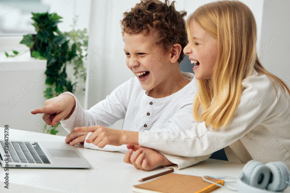 Happy Children Studying Online at Home Using Laptops in a Cozy Living Room Happy Children Studying Online at Home Using Laptops in a Cozy Living Room