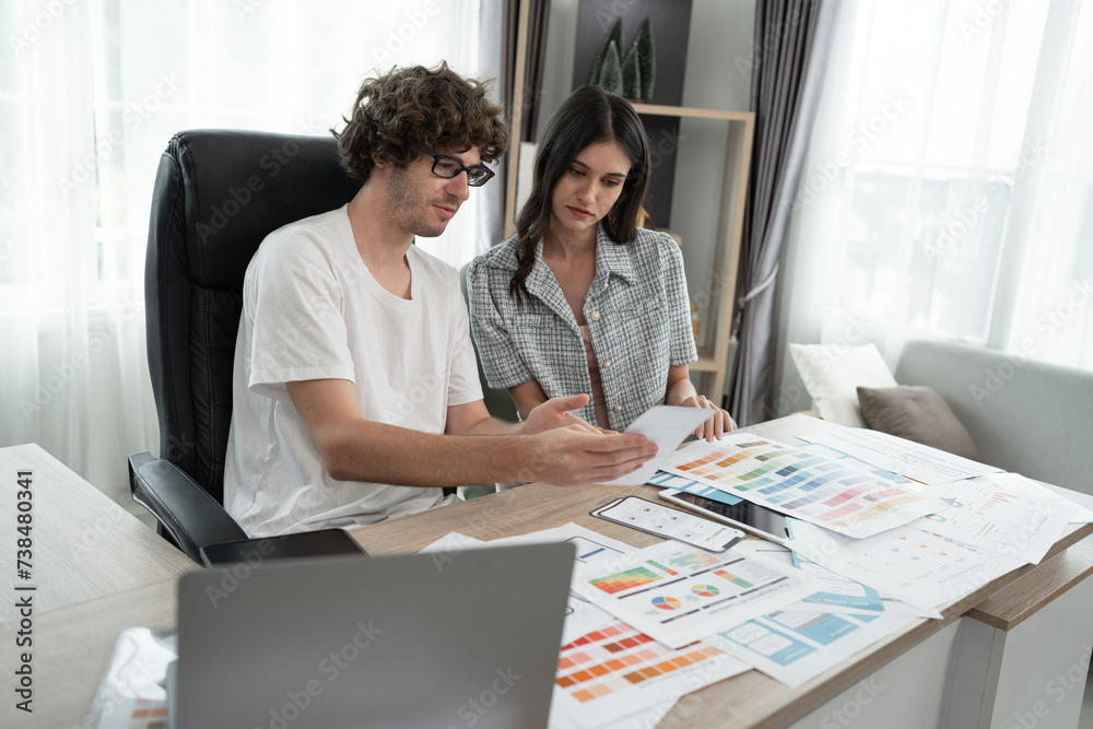 Caucasian businessman and Asia businesswoman working with color chart at office	