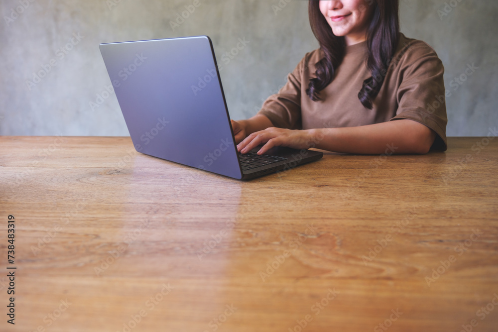 Closeup image of a young woman working on laptop computer on wooden table at home Closeup image of a young woman working on laptop computer on wooden table at home