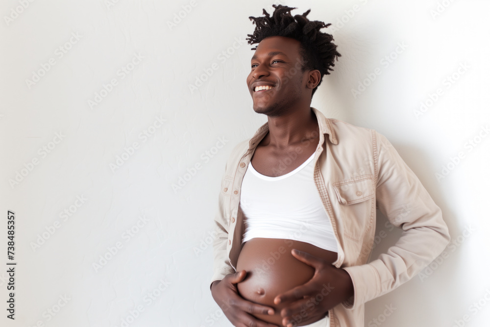 A pregnant, black, transgender African American man holding his belly against a white background with room for text.  - obrazy, fototapety, plakaty 