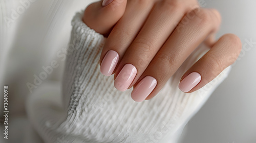 A woman's hand with short mindal nails painted in soft pink, Soft light, creating a feminine and sophisticated atmosphere. photo