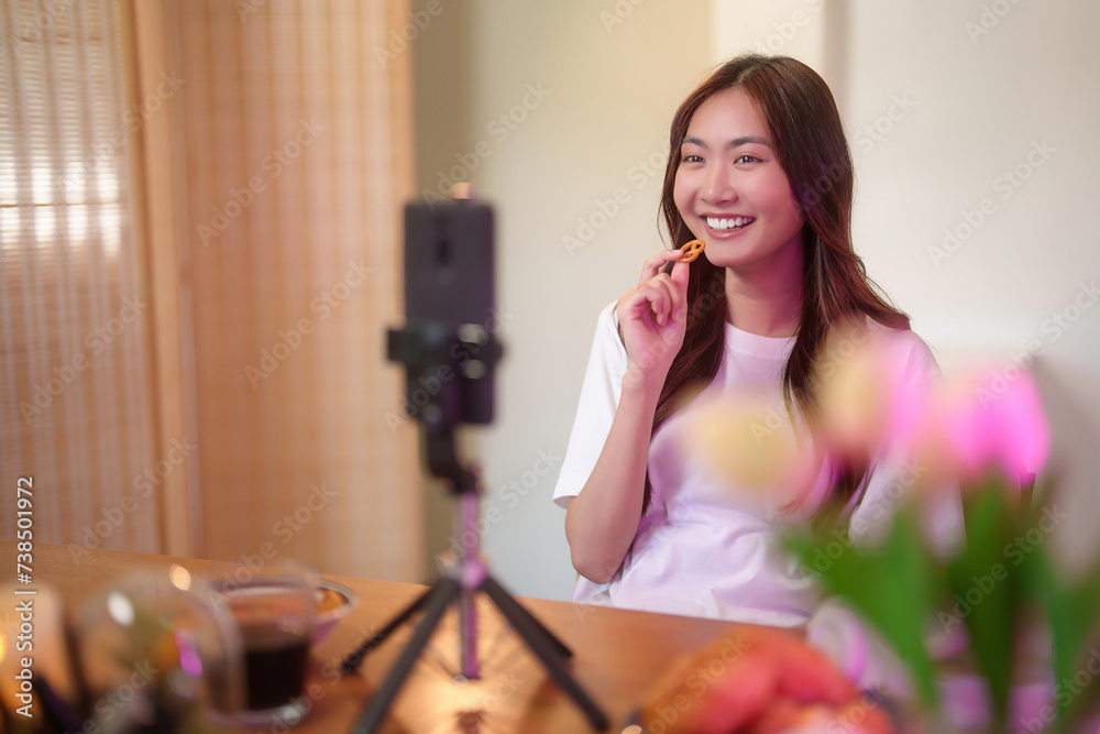 Young asian vj women use digital smartphone and recording video to speaking morning talks about news in live streaming on channel while eating snack and working with happiness at home studio Young asian vj women use digital smartphone and recording video to speaking morning talks about news in live streaming on channel while eating snack and working with happiness at home studio