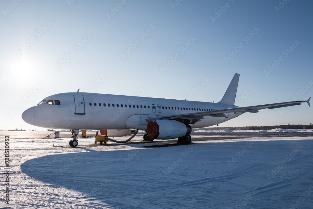 White passenger jetliner on the airport apron at winter White passenger jetliner on the airport apron at winter