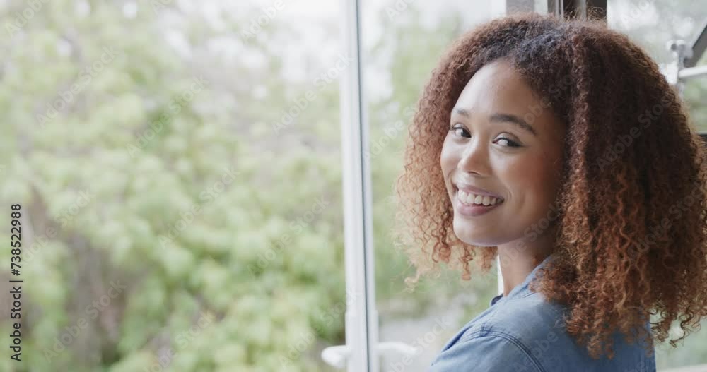 Young African American woman smiles near a window at home, with copy space Young African American woman smiles near a window at home, with copy space