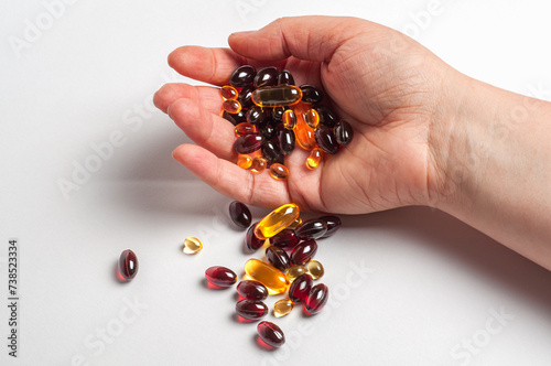Hand Holding Various Nutritional Supplements Against a White Background photo