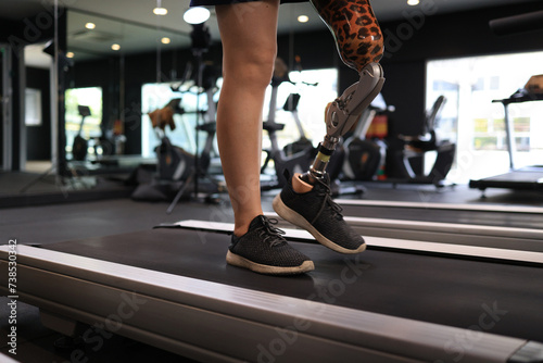Low angle view at woman with prosthetic leg walking in treadmill at fitness gym © naraichal