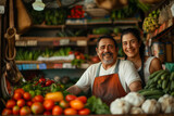 Two joyful market vendors stand behind a vibrant display of fresh produce, sharing a smile in a bustling marketplace.