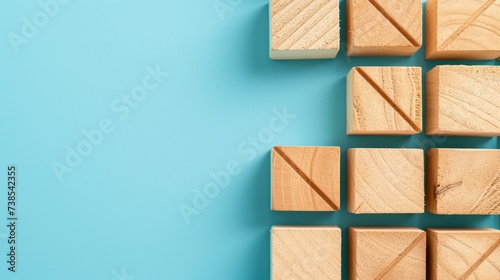 Wooden blocks with an arrow at the bottom, featuring minimalist grids in sky-blue hues, embodying minimalist precision, socially engaged work, and the use of common materials. photo