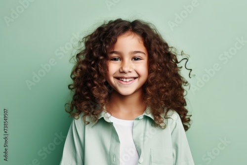 Smiling little girl with curly hair looking at camera over green background